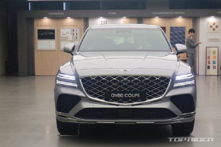 Đầu xe sang Genesis GV80 Coupe nổi bật với lưới tản nhiệt Crest cỡ lớn, được bổ sung mắt lưới G-matrix 2 lớp nhằm nhấn mạnh hình ảnh hiệu suất cao của mẫu SUV lai Coupe này. Bên dưới lưới tản nhiệt là 4 khe gió hẹp vừa giúp xe nhìn thể thao, khỏe khoắn hơn lại giúp tối ưu hóa khả năng làm mát động cơ cho xe.