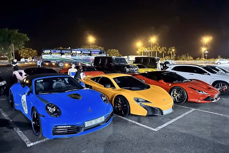 Trong ảnh là các siêu xe, xe thể thao xếp hàng trước trạm dừng chân trên cao tốc, từ trái sang là Porsche 911 Targa, McLaren 650S Coupe, Ferrari F8, hàng dưới có Ferrari 812 Superfast màu vàng, Mercedes-AMG G63, Audi R8 V10 Plus màu đỏ và Ferrari 488 Spider màu hồng