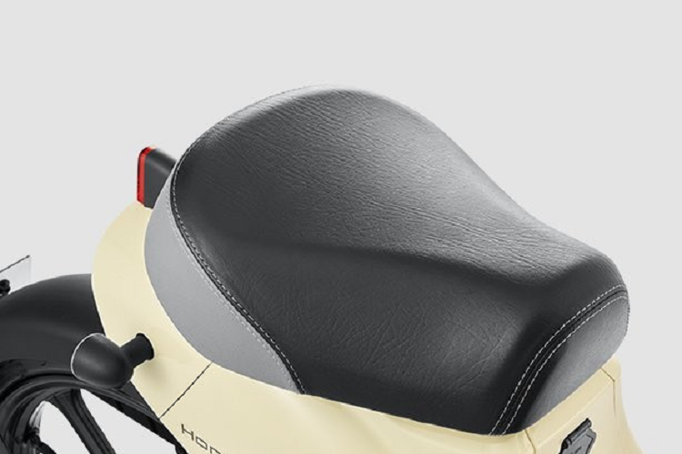 Điểm nhấn tiếp theo của Honda Cub e: là đồng hồ kỹ thuật số với màn hình LCD có thiết kế tương tự đồng hồ nguyên bản của Super Cub. Bảng đồng hồ này giúp người điều khiển dễ dàng quan sát nhờ sự tương phản mạnh. Bên cạnh đó, bảng đồng hồ còn tích hợp đèn nền tự động điều chỉnh, kết nối với công tắc đèn pha.