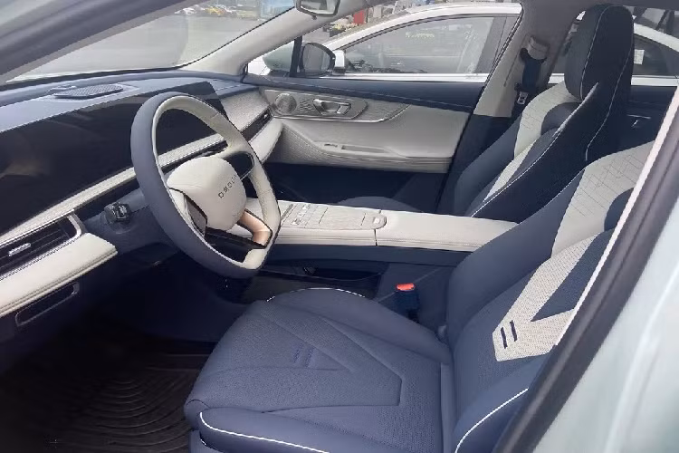 Bên cạnh đó, xe còn đi kèm cụm điều khiển trung tâm khác với phiên bản máy xăng. Ở khu vực này chỉ có 2 thanh cuộn chỉnh âm lượng, màn hình giải trí và chọn chế độ lái. Nội thất của OMODA 5 e-QUA được bọc da và ốp gỗ nhằm tạo cảm giác cao cấp. Ghế trước của xe có thiết kế thể thao trong khi hàng ghế sau có đủ chỗ cho 3 người ngồi và đi kèm cửa gió điều hòa. 