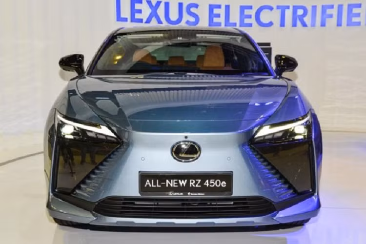 Ở phần đầu xe, SUV điện Lexus RZ450e vẫn có tạo hình mặt ca-lăng với bộ lưới tản nhiệt giả hình con suốt quen thuộc. Bề mặt lưới tản nhiệt được làm nhẵn, trong khi các cạnh bên là những đường gờ đẹp mắt nhấn mạnh vào kiểu thiết kế hình con suốt đã đi theo Lexus từ rất lâu. Nằm đối xứng hai bên vẫn là cụm đèn pha vuốt nhọn đầy sắc sảo kết hợp cùng nắp capo dập nổi nhẹ nhàng làm tăng thêm vẻ tinh tế và cá tính cho “khuôn mặt” của RZ 50e.