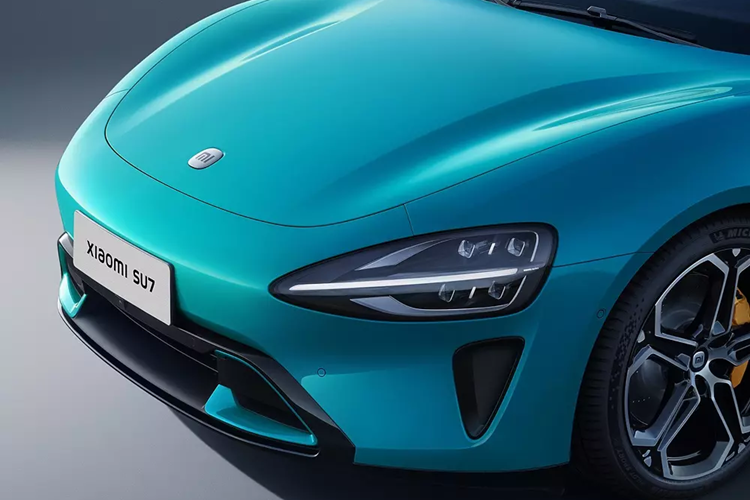 Tiếp theo đó là cản trước tích hợp hốc gió trung tâm hình thang, trang trí bằng viền sơn cùng màu thân xe, và khe gió hình tam giác ở hai góc. Xiaomi SU7 tuy là xe sedan nhưng lại sở hữu nóc dốc về phía sau theo phong cách coupe, mang đến cảm giác mượt mà và khí động lực học.