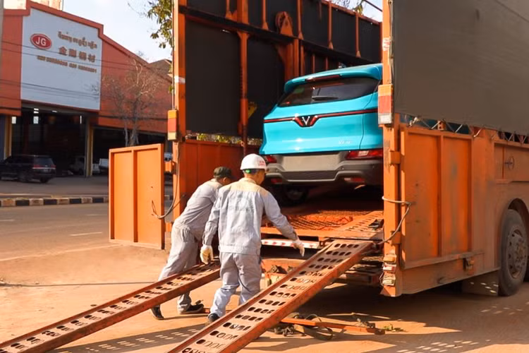 Những chiếc xe điện VinFast đang được hoàn thiện những bước chuẩn bị cuối cùng trước khi sẵn sàng lăn bánh. Trong ảnh là công đoạn dán decal song ngữ thông tin về tổng đài của taxi Xanh SM tại Lào.