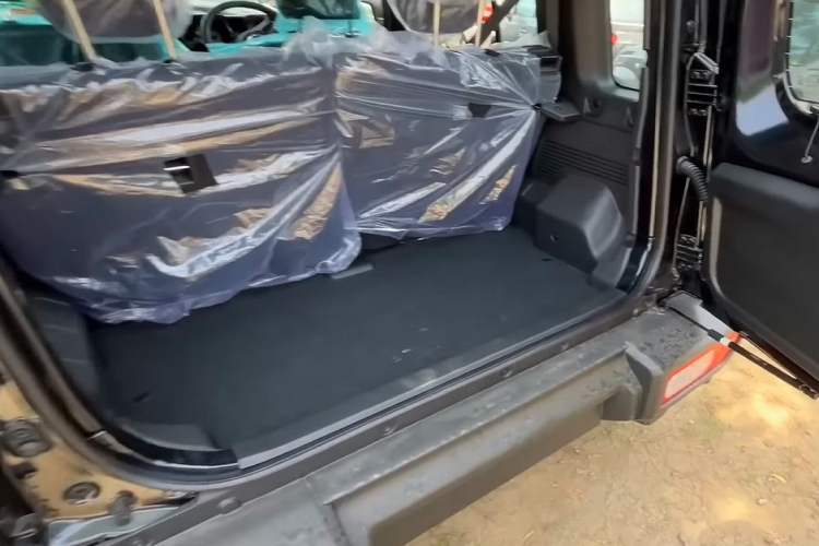 Suzuki Jimny Zeta 5 cửa được trang bị vô lăng tích hợp một vài nút bấm và chỉnh 2 hướng lên/xuống. Bên cạnh đó là bảng đồng hồ analogue với màn hình đa thông tin nhỏ ở giữa, màn hình cảm ứng trung tâm 7 inch, hỗ trợ kết nối Apple CarPlay/Android Auto không dây... hệ thống điều hòa chỉnh tay, gương chiếu hậu chỉnh 2 chế độ ngày/đêm, kính cửa sổ chỉnh điện và khởi động máy bằng chìa khóa cơ.