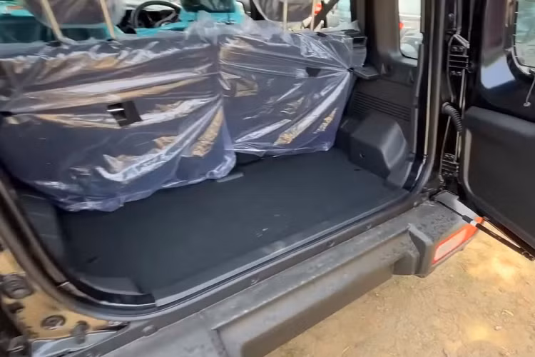 Suzuki Jimny Zeta 5 cửa được trang bị vô lăng tích hợp một vài nút bấm và chỉnh 2 hướng lên/xuống. Bên cạnh đó là bảng đồng hồ analogue với màn hình đa thông tin nhỏ ở giữa, màn hình cảm ứng trung tâm 7 inch, hỗ trợ kết nối Apple CarPlay/Android Auto không dây... hệ thống điều hòa chỉnh tay, gương chiếu hậu chỉnh 2 chế độ ngày/đêm, kính cửa sổ chỉnh điện và khởi động máy bằng chìa khóa cơ.