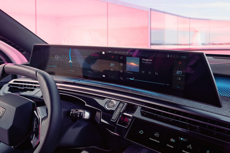 Tiếp theo đó là vô lăng vát 2 đầu nhỏ gọn, màn hình cảm ứng nằm ở cụm điều khiển trung tâm để chỉnh các tính năng của xe và hệ thống đèn viền nội thất ấn tượng trên mặt táp-lô. Cụm điều khiển trung tâm của xe được đặt cao, tạo thành vách ngăn giữa 2 ghế trước và tích hợp một số nút bấm chỉnh điều hòa, phanh tay điện tử cũng như giá để ly. Trong khi đó, các nút bấm chuyển số của xe được đặt dọc bên cạnh nút bấm khởi động máy.