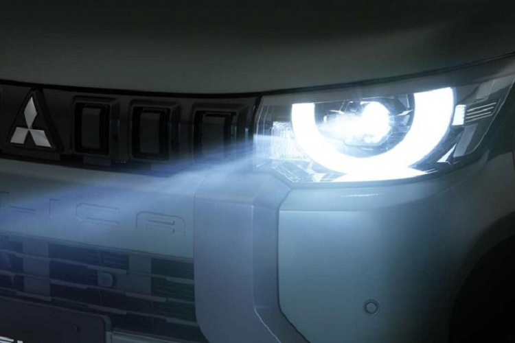 Phía dưới là dòng chữ "Delica" được dập chìm và lưới tản nhiệt bao quanh bằng nẹp dày dặn, tích hợp đèn sương mù trước. Trong khi đó, cản trước được sơn màu đen với hốc gió trung tâm và ốp màu bạc tạo cảm giác rắn rỏi cho khu vực đầu xe.