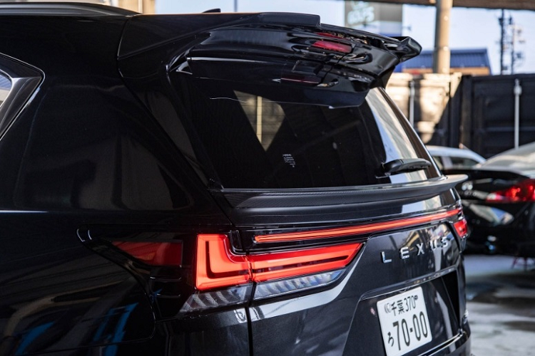 Phía đầu xe, Lexus LX600 độ Liberty Walk vẫn sử dụng thanh tản nhiệt nằm ngang đặc trưng nhưng được sơn lại thành màu đen bóng thay vì màu bạc như trước. Phần nắp capo được hãng độ nước Nhật nâng cấp thêm các khe thoát gió.