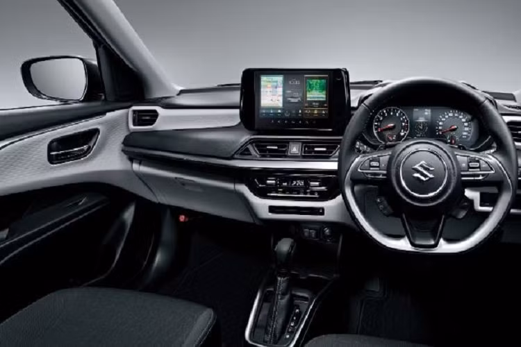 Chiếc Suzuki Swift 2024 trong hình ảnh do hãng tung ra được sơn màu xanh dương với nóc đen tương phản. Trên nóc vẫn là ăng ten dạng cột như thế hệ cũ. Bên trong xe cũng được thổi làn gió mới, với những trang bị hiện đại hơn như màn hình hiển thị thông tin kính lái HUD, màn hình cảm ứng trung tâm 9 inch, điều hòa tự động 1 vùng và cổng USB. 