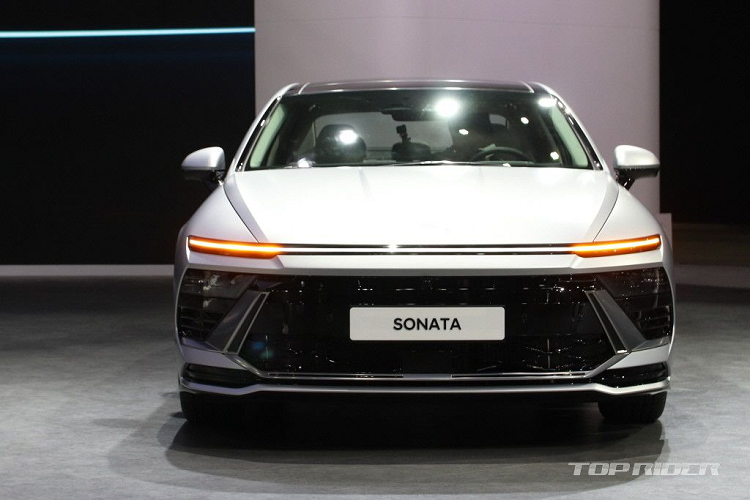 Tiếp đến là lưới tản nhiệt hẹp, tách riêng với hốc gió trung tâm hình chữ nhật phía dưới bằng nẹp màu đen bóng ở giữa. Bên cạnh đó, nắp capo của xe cũng được tạo hình lại với các đường gân nổi thể thao. Logo của hãng cũng đã được chuyển vị trí trung tâm lưới tản nhiệt lên trên nắp ca-pô, tương tự phong cách của Hyundai Accent thế hệ mới.