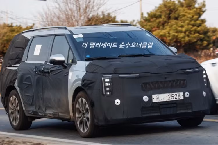 Lần này, xe vẫn được ngụy trang nhưng lộ rõ nhiều chi tiết hơn trước. Đúng như dự đoán từ trước đó, mẫu xe MPV Kia Carnival 2024 sẽ được áp dụng ngôn ngữ thiết kế mới của thương hiệu Kia. Điều này được thể hiện qua lưới tản nhiệt cỡ lớn hơn với mắt lưới mới trên đầu xe.Ở hai bên lưới tản nhiệt là cụm đèn pha nằm dọc, tương tự mẫu SUV thuần điện cỡ lớn Kia EV9 2024 mới ra mắt