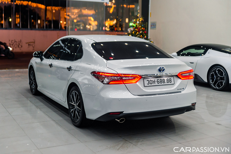 Ngoại thất của chiếc Camry 2.5HV sở hữu màu sơn trắng ngọc trai. Phần đầu xe có thiết kế mới với lưới tản nhiệt cỡ lớn, tách biệt rõ ràng hơn với cản trước. Đi kèm nan nằm ngang màu đen hoặc xám, kéo dài sang hai bên. Bao quanh lưới tản nhiệt là đường viền hình chữ C.