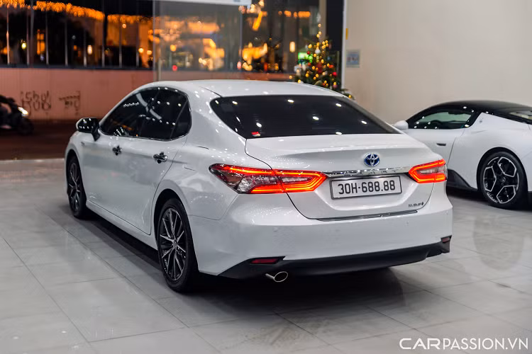 Ngoại thất của chiếc Camry 2.5HV sở hữu màu sơn trắng ngọc trai. Phần đầu xe có thiết kế mới với lưới tản nhiệt cỡ lớn, tách biệt rõ ràng hơn với cản trước. Đi kèm nan nằm ngang màu đen hoặc xám, kéo dài sang hai bên. Bao quanh lưới tản nhiệt là đường viền hình chữ C.