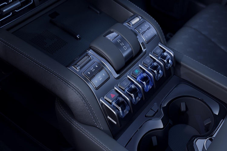 Khi người lái tắt máy, cần số sẽ dần hạ xuống, mang đến cảm giác đặc biệt hơn. Ngoài ra, ở cụm điều khiển trung tâm còn có 2 thanh cuộn để chọn chế độ của hệ dẫn động 4 bánh, các phím chức năng như phím đàn piano, sạc điện thoại không dây 50W, phanh tay điện tử và 2 giá để ly.