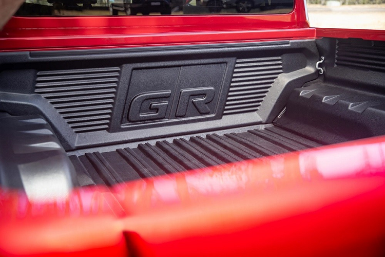 Bên trong Toyota Hilux GR Sport 2023 là không gian nội thất có màu đen chủ đạo. Tất nhiên, xe vẫn có những điểm nhấn như bộ bàn đạp thể thao bằng kim loại và dây đai an toàn màu đỏ. Phía sau vô lăng còn có thêm lẫy chuyển số thể thao.