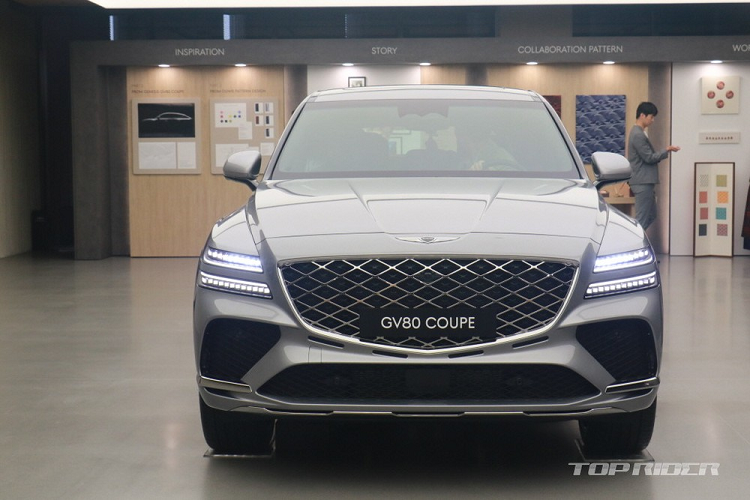 Cản trước của Genesis GV80 Coupe 2024 được trang bị 3 hốc gió rộng hơn GV80. Trong khi đó, nằm bên dưới lưới tản nhiệt là 4 khe gió hẹp mới để vừa tối ưu hóa khả năng làm mát động cơ vừa tạo ra thiết kế thể thao cho xe. Vành la-zăng của mẫu SUV lai Coupe này có thiết kế riêng, không giống Genesis GV80 thông thường. Tùy theo phiên bản, xe sẽ dùng vành 20 inch hoặc 22 inch.