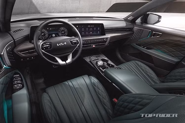 Nội thất Kia K8 chào đón người dùng bằng không gian vô cùng hiện đại và sang trọng không kém những chiếc xe Đức, với độ hoàn thiện đẹp mắt và tỉ mỉ trên bề mặt gỗ lấy cảm hứng từ du thuyền. Xe được trang bị màn hình cong tích hợp màn hình giải trí trung tâm cỡ lớn và màn hình cụm đồng hồ kỹ thuật số 12 inch.