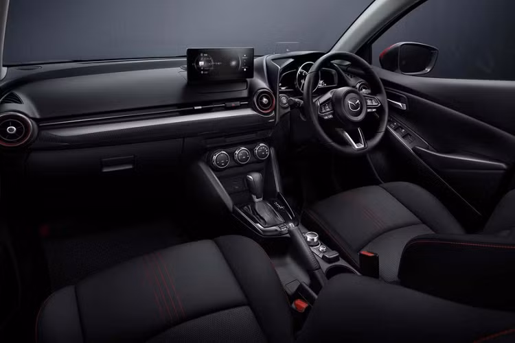 Màn hình của Mazda2 2024 vẫn có thiết kế như máy tính bảng và đặt nổi thay vì tích hợp gọn gàng vào mặt táp-lô. Với hệ thống thông tin giải trí mới, người dùng có thể thực hiện các cuộc gọi khẩn cấp hoặc tư vấn, định vị xe và điều khiển một số tính năng từ xa thông qua điện thoại thông minh.