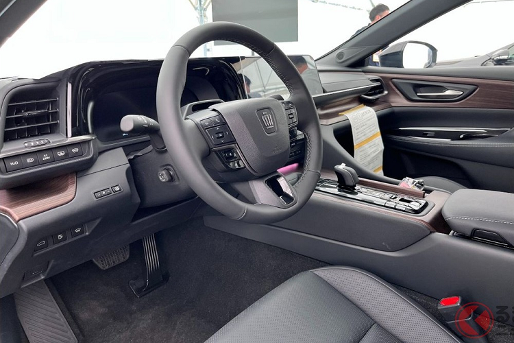 Vì Toyota Crown Sedan 2024 là xe dẫn động cầu sau nên bên trong nội thất có trục truyền động chạy dọc khá lớn, ảnh hưởng đến không gian của khoang hành khách đồng thời khiến cụm điều khiển trung tâm nằm khá cao, tạo thành vách ngăn giữa 2 ghế trước. Trên cụm điều khiển trung tâm có cần số ngắn, sạc điện thoại không dây, phanh tay điện tử và 2 ngăn đựng cốc.