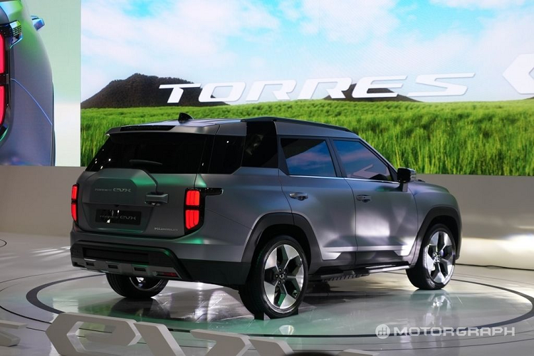 Tương tự như phần đầu xe, cản sau cũng có ốp gầm màu bạc. Về nội thất, KG Mobility Torres EVX được trang bị màn hình cong cỡ lớn kéo dài, đặt nổi trên mặt táp-lô. Màn hình này tích hợp bảng đồng hồ kỹ thuật số và màn hình cảm ứng trung tâm 12,3 inch. Vô lăng vát đáy thể thao, mặt táp-lô của xe được ốp gỗ trong khi bên dưới có nẹp trang trí màu bạc mang đến cảm giác cao cấp.