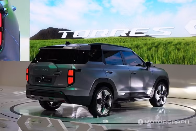 Tương tự như phần đầu xe, cản sau cũng có ốp gầm màu bạc. Về nội thất, KG Mobility Torres EVX được trang bị màn hình cong cỡ lớn kéo dài, đặt nổi trên mặt táp-lô. Màn hình này tích hợp bảng đồng hồ kỹ thuật số và màn hình cảm ứng trung tâm 12,3 inch. Vô lăng vát đáy thể thao, mặt táp-lô của xe được ốp gỗ trong khi bên dưới có nẹp trang trí màu bạc mang đến cảm giác cao cấp.