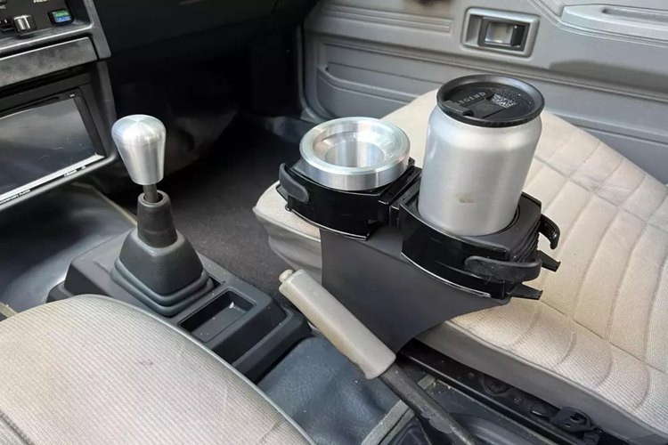 Tiếp đến là hệ thống đèn pha tròn cổ điển, đây nhiều khả năng là chi tiết đã được độ lên, cản trước của Toyota Corolla II GL 1985 rất thú vị, nó be ra và vuông vức, tạo nên sự cá tính và hầm hố cho đời này. Vòng ra bên sườn, chiếc xe của ông Đặng Lê Nguyên Vũ đã được độ lại bộ mâm. Đằng sau xe với thiết kế hatchback 3 cửa rất thú vị, cùng quả cánh gió mui xe. 