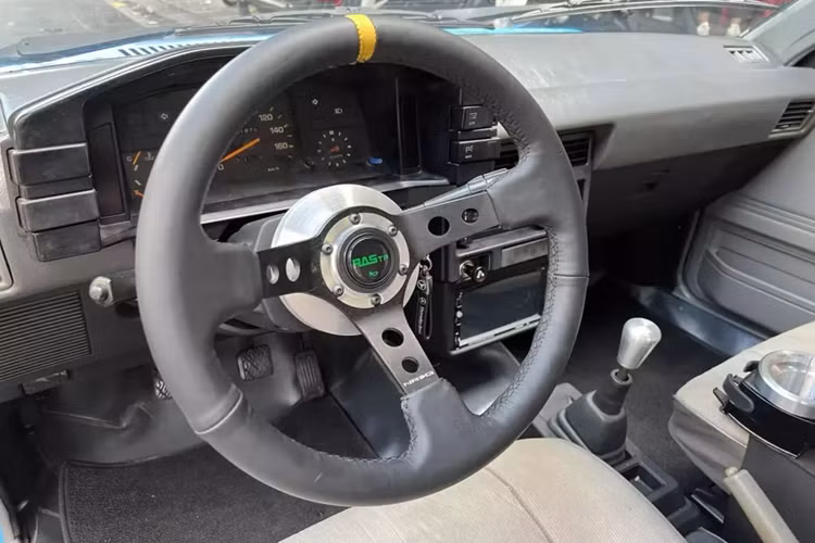 Mở cửa bước vào trong khoang lái, các ghế ngồi trên xe Toyota Corolla II GL 1985 của ông Đặng Lê Nguyên Vũ được bọc 2 màu da là be và xám, vì có thiết kế hatchback 3 cửa, nên khoảng trống của hàng ghế sau đủ chỗ cho 3 người lớn ngồi thoải mái. Nhưng có lẽ nó ít khi được chở người. Ở khoang lái, có 2 điểm gây chú ý cho người xem, đó là việc xe đã được thay vô lăng độ RASTP có kích thước 13 inch, và quan trọng là quả độ hộp đựng tàn xì gà và bình đựng cà phê. 