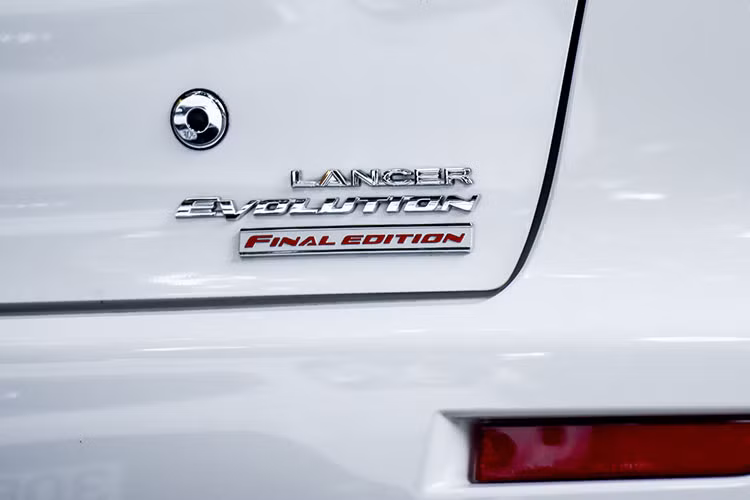 Ở phía sau, Mitsubishi Lancer EVO Final Edition càng toát lên vẻ hầm hố, thể thao với cánh gió cố định khá lớn ở đuôi xe. Cụm đèn hậu halogen được thiết kế mảnh mai, sắc xảo. Để tăng độ nhận diện, chiếc sedan bản giới hạn này còn được tích hợp logo “Lancer Evolution Final Edition” trên cửa cốp. Sâu xuống phía dưới là cản sau màu đen cùng ống xả đơn đặt đối xứng 2 bên.