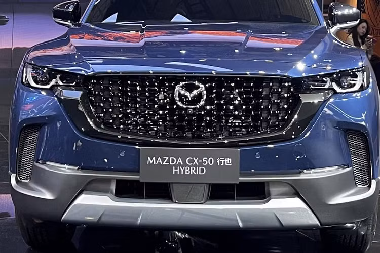 Mazda CX-50 hybrid vẫn có mặt trước áp dụng thiết kế theo phong cách gia đình mới nhất của Mazda, với lưới tản nhiệt phẳng và rộng cùng đèn pha LED hoàn toàn mới, 2 bên đầu xe có hốc gió dựng đứng, và dù mang màu mới hay cũ, cản va trước/sau, vòm bánh xe hay nẹp sườn cũng là nhựa màu đen nhám.