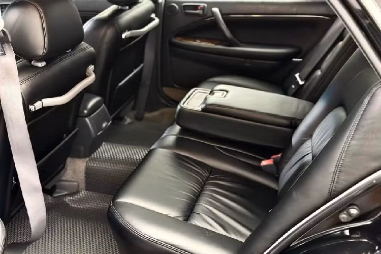 Ngoài ra bệ tì tay ở giữa có thể gập, trang bị sẵn hai hộc để cốc và khay chứa đồ cá nhân. Điều hòa được bố trí ở trần xe cùng đèn đọc sách. Là một mẫu xe gần 30 năm tuổi nên các trang bị của Toyota Crown nằm ở mức đủ dùng. Chiếc xe trong bài viết thậm chí còn giữ lại hệ thống giải trí đầu đọc đầu đọc băng cassette, ở thời điểm đó chưa có đầu đĩa CD.