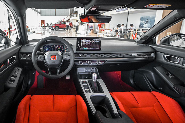 Bên trong, Civic Type R 2023 sở hữu nội thất tông đen – đỏ đậm chất thể thao đặc trưng. Xe được trang bị màn hình giải trí trung tâm kích cỡ 9 inch kết nối Apple Carplay/ Android Auto và cụm đồng hồ kỹ thuật số 10,2 inch. Hộp số sàn 6 cấp tương tự thế hệ trước, kết hợp tính năng Rev Matching với khả năng điều chỉnh vòng tua máy khi sang số.