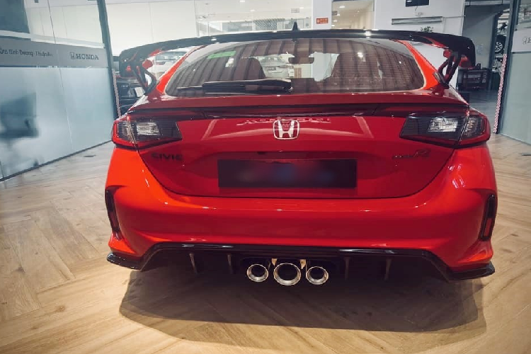 Dù vậy, Honda Civic Type R 2023 mang màu đỏ Rallye Red cũng khá hiếu chiến, điểm nhấn của xe còn có rất nhiều chi tiết sơn đen như cản trước/sau, vỏ gương, viền cửa kính, bộ mâm đa chấu kép 19 inch sơn đen nhám và cuối cùng, cánh gió đuôi khổng lồ của xe.