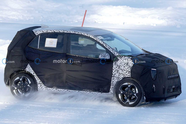 Dọc theo hai bên sườn, Kia Morning facelift có đường nổi hông nâng dần về phía sau được làm nhô lên cao hơn một chút so với phiên bản hiện hành. Vì Kia che chắn toàn bộ khu vực này nên không rõ hãng có thay đổi gì khác tại cửa hay không.