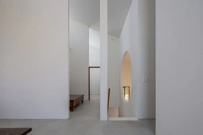 Thông qua ô mở tròn, gian thờ có hướng nhìn mở rộng xuống không gian thông tầng phía dưới, tạo thành trục không gian chính, kết nối mặt nước và cảnh quan phía Nam với ánh sáng dịu nhẹ từ hướng Bắc qua cửa sổ áp mái. Ảnh: Hoàng Lê, Đức Ngô