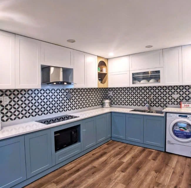 Khu vực tủ bếp dưới còn tích hợp ô để máy giặt tiện nghi, là giải pháp phổ biến cho những ngôi nhà có diện tích nhỏ. Ảnh: Nguyễn Nhung Tầng lửng là không gian phòng ngủ của gia đình. Để tối ưu được diện tích và công năng, nhóm kiến trúc sư đã bố trí hệ tủ lùa liền giường. Đối diện giường là bàn học, được trổ thêm một ô cửa nhỏ xinh giúp kết nối với không gian dưới nhà.