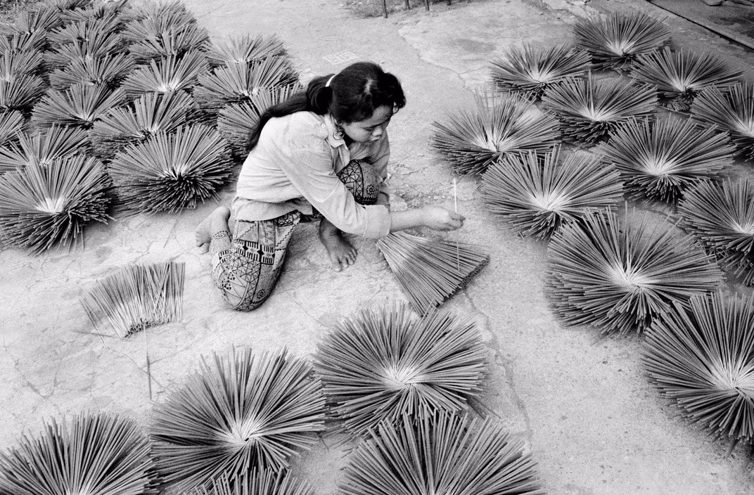 Người phụ nữ xếp các bó hương trầm trên sân để phơi khô ở thành phố Vientiane, 11/4/1991. Ảnh: John Vink / Magnum Photos.