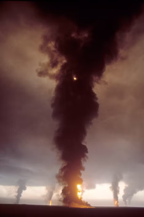 Các cột khói đen khổng lồ phun lên trời từ các giếng dầu bốc cháy. Ảnh: Bruno Barbey / Magnum Photos.