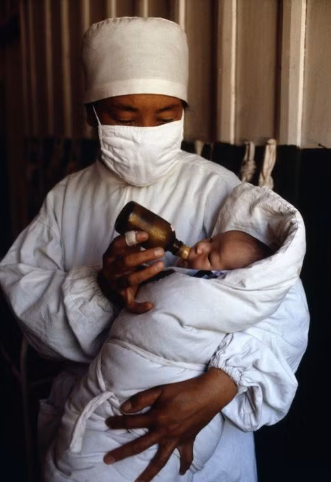 Bác sĩ cho trẻ sơ sinh bú bình. Ảnh: Eve Arnold / Magnum Photos.
