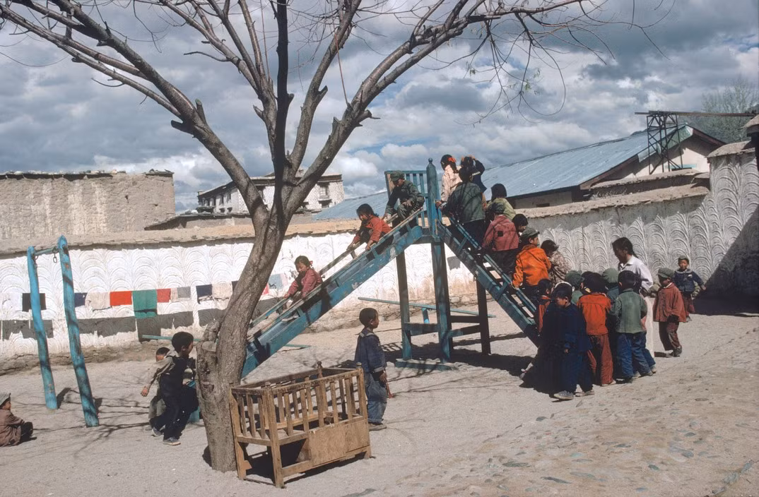 Trẻ em xếp hàng để chơi trượt cầu trượt tại sân chơi của một hợp tác xã ở thành phố Lhasa. Ảnh: Eve Arnold / Magnum Photos.