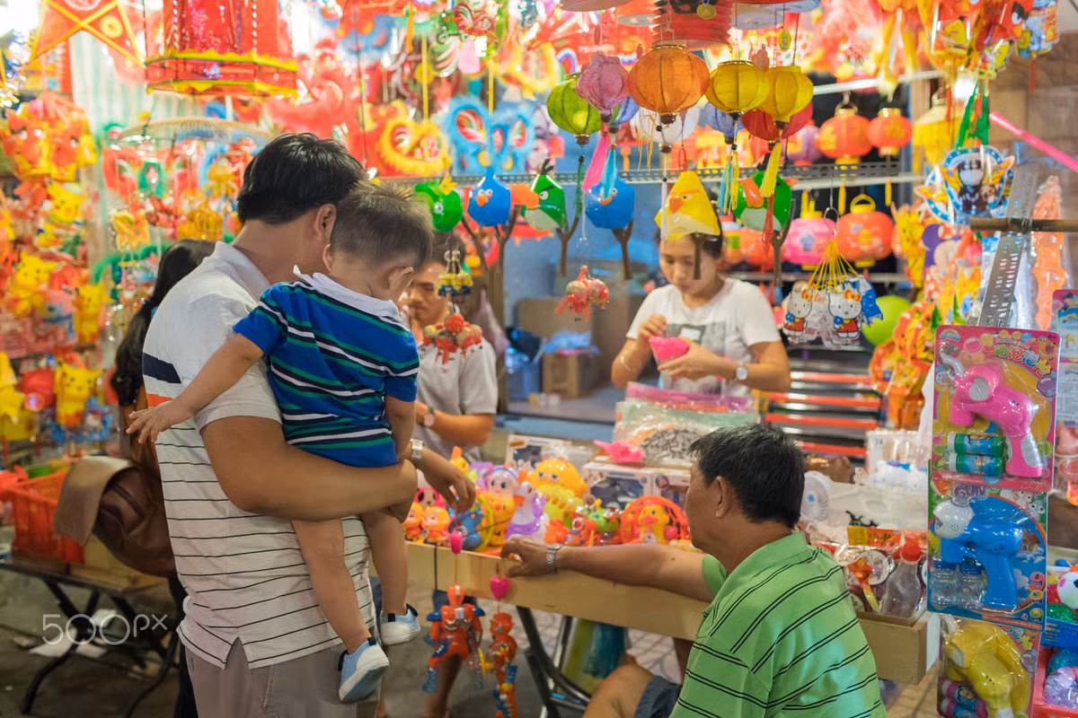 Một em bé được bố mua đồ chơi Trung thu. Ảnh: Yan Lerval/ 500px.com.