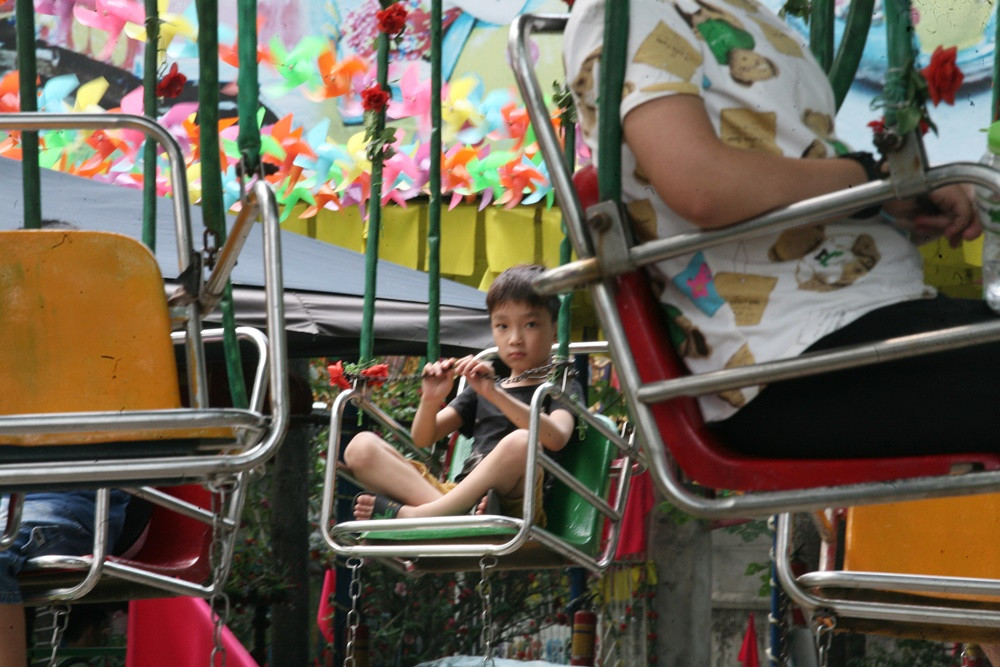 Em nhỏ rầu rĩ dù đang ngồi chơi đu quay.