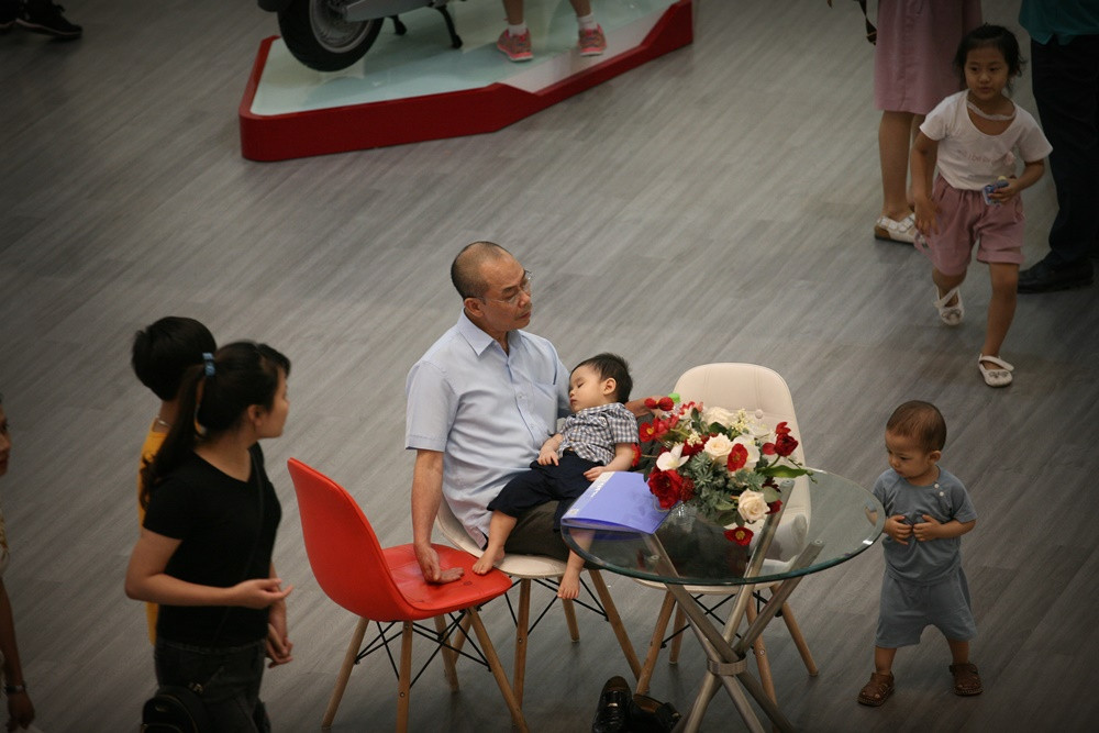 Một em nhỏ mệt nhoài ngủ trên đùi bố.