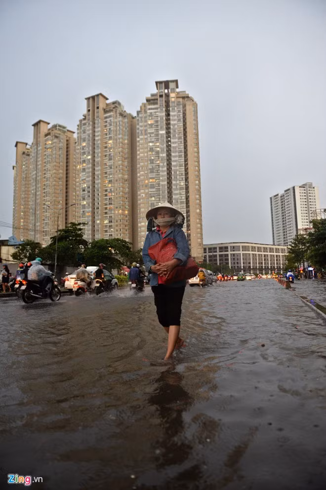 Chị Nguyễn Thị Nhỏ, làm công nhân vệ sinh trong tòa nhà Saigon Pearl lội nước bắt xe buýt về nhà sau giờ làm việc.
