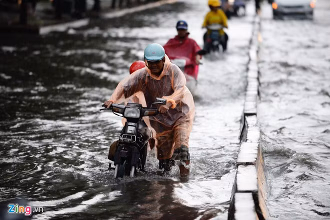 Nước ngập nửa bánh xe, người dân bì bõm lội nước trong cơn mưa chiều.