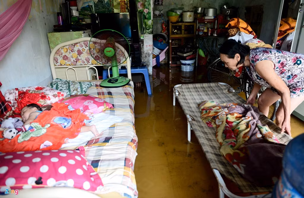 Đứa cháu ngủ ngon lành trong phòng trọ đầy nước, bà Mai Thị Như sắp xếp lại đồ đạc nhưng chưa thể làm được gì nhiều vì nước rút rất chậm. "Không có tiền thuê chỗ cao đẹp hơn nên phải sống chung thôi. Mỗi lần mưa lớn cả xóm rất khổ cực. Ai cũng nháo nhào như chạy lũ", người phụ nữ này, chia sẻ.