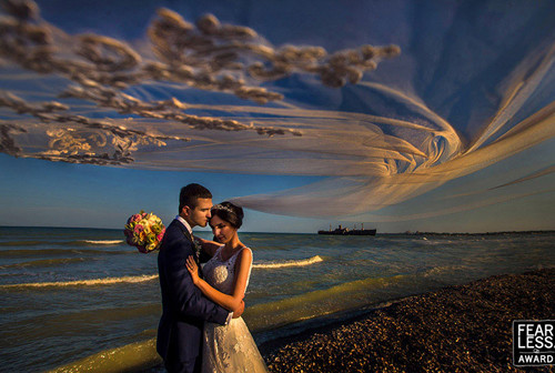 Dải voan như những đám mây mong manh trên nền bầu trời về tối kết hợp hoàn hảo với bờ cát sỏi sẫm màu và hình con tàu xa xa để làm nổi bật hai nhân vật chính.