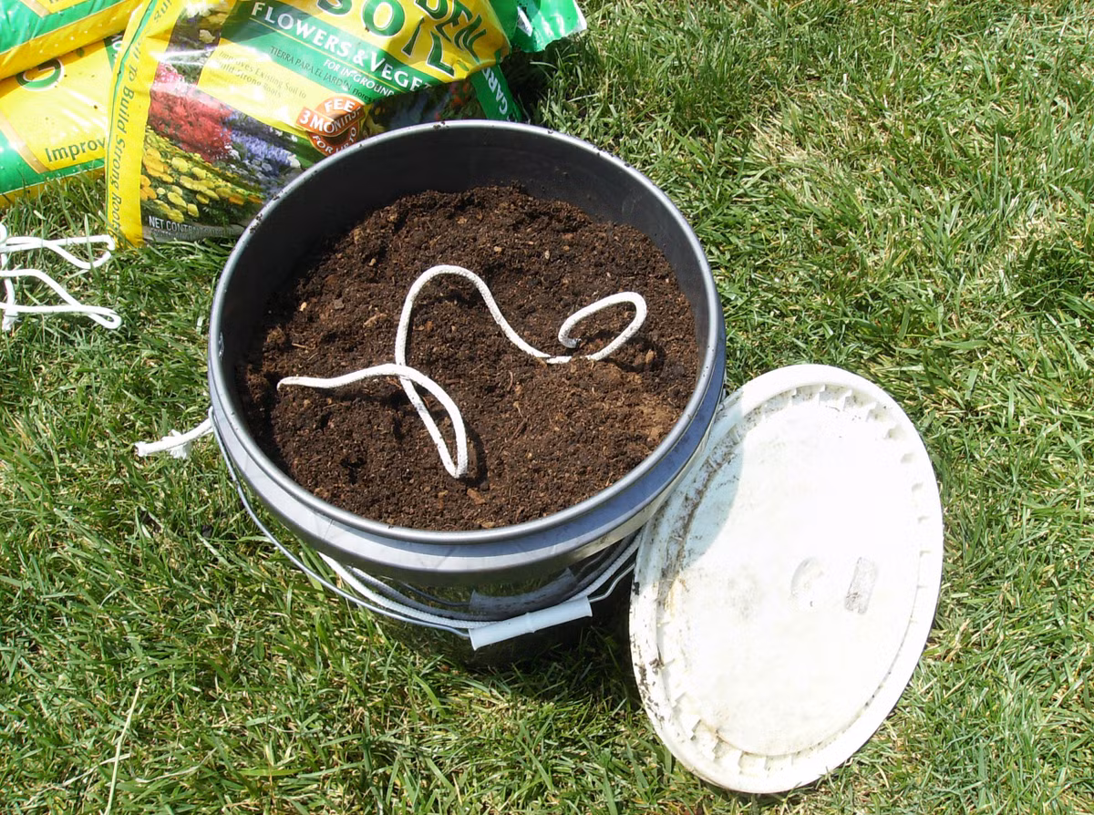 Bước 3: Bạn bỏ cây cà chua ra ngoài, lật ngược chậu trồng và đổ đất dinh dưỡng đã được làm sạch, tơi xốp. Đừng quên dùng lá cây hoặc mảnh nilon nhỏ đậy vết cắt phía đáy chậu. Sau khi đổ đất, đậy nắp chậu trồng khi bạn lật ngửa chậu trở lại.