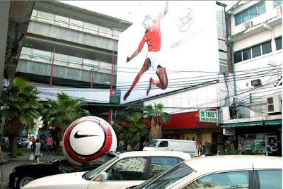 Một tấm biển quảng cáo ấn tượng của Nike. Cầu thủ sút bóng và quả bóng khiến cho chiếc ô tô phía dưới bẹp rúm.