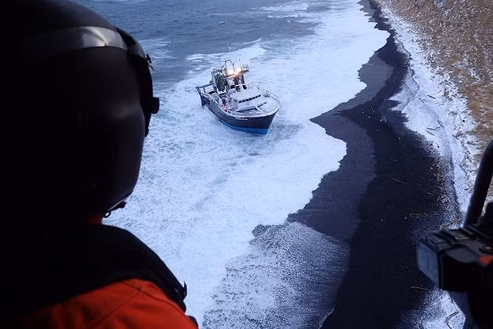 Trực thăng MH-60 Jayhawk thăm dò khu vực quanh tàu đánh cá này trước khi kéo nhấc 3 người ra khỏi đó.