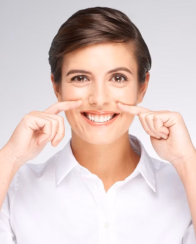 Bước 2: Cười kiểu hơi nghiến răng nhẹ, dùng 2 ngón trỏ massage xung quanh viền miệng cười. Giữ và đếm đến 6 giây, sau đó lặp lại quy trình.